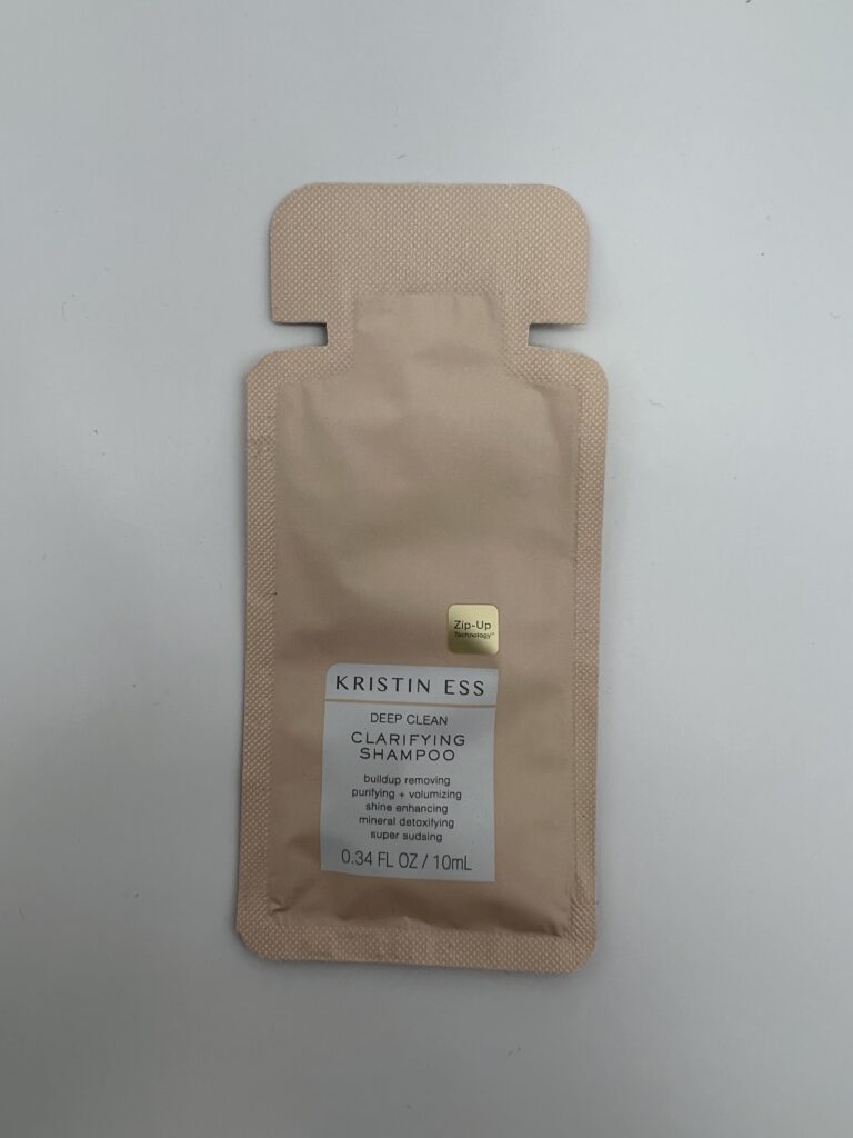 A sealed beige pouch with a label and a small gold sticker.