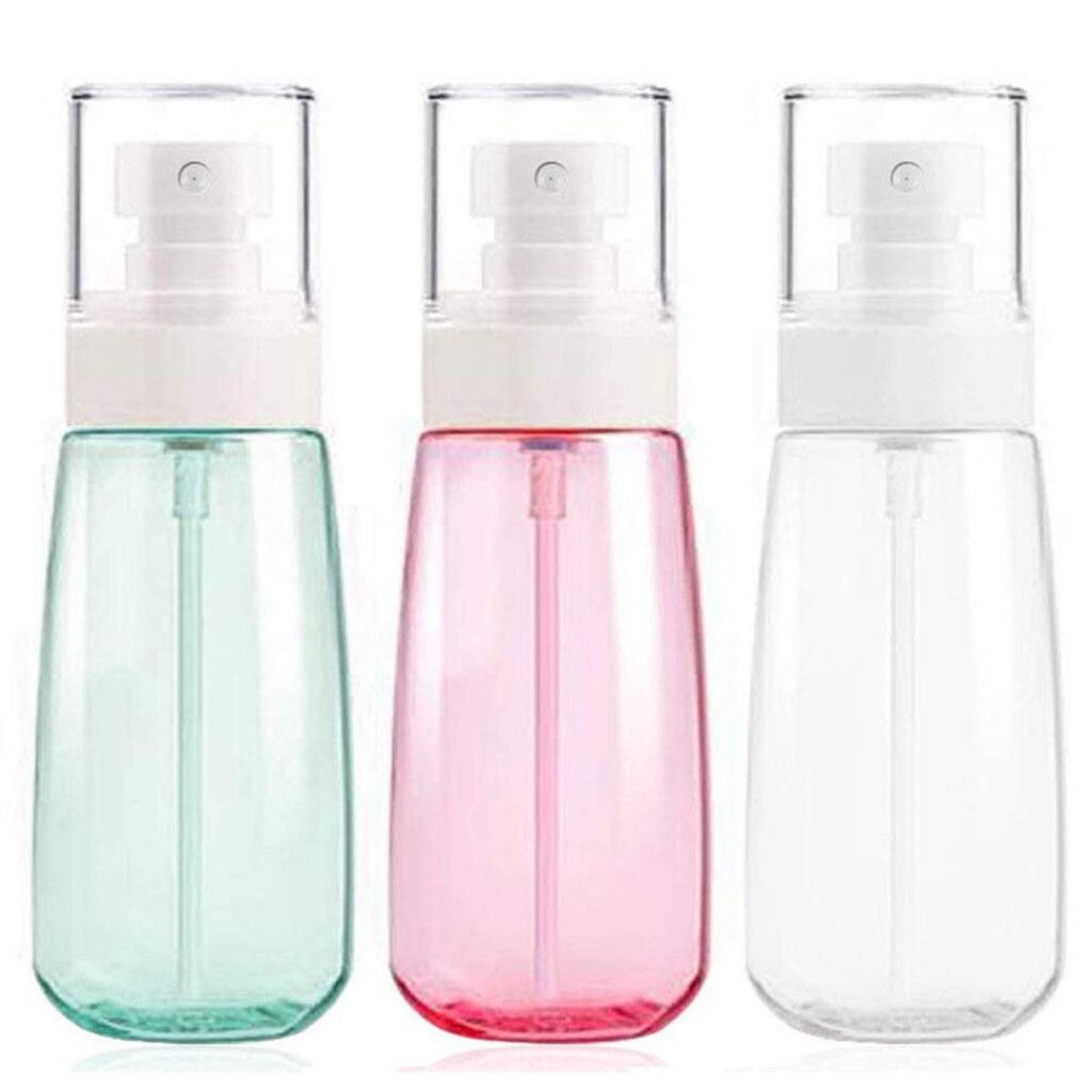 Three small spray bottles in green, pink, and clear colors.