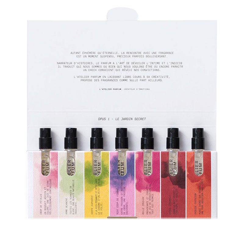 Eight colorful perfume sample sprays arranged in front of a white card with text.