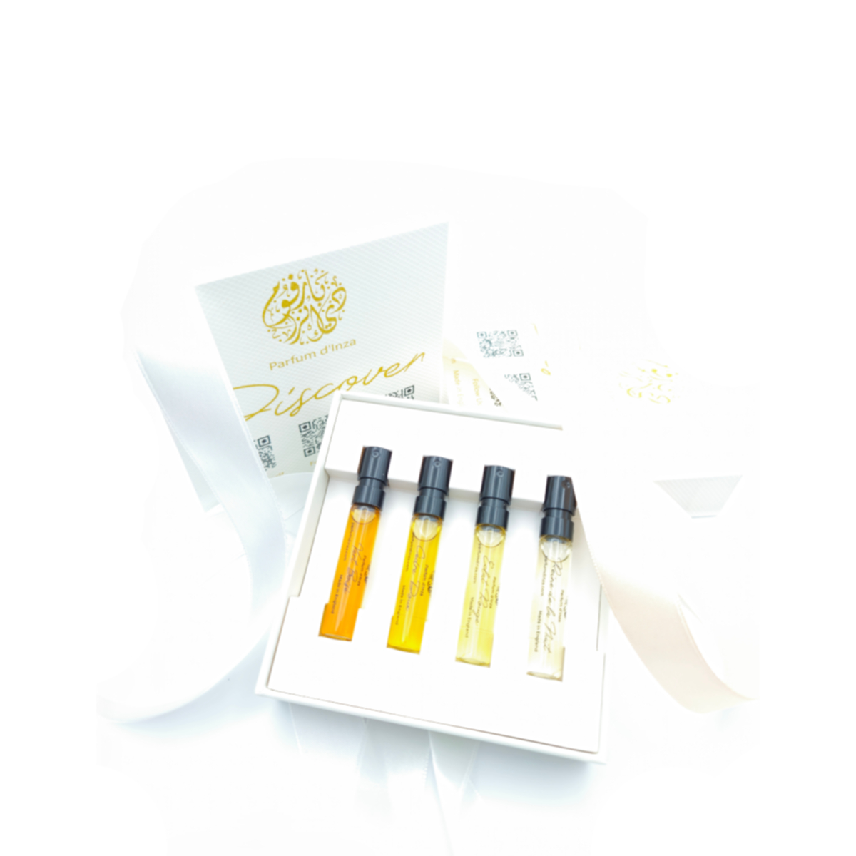 A set of four perfume sample vials in a white box with a ribbon.