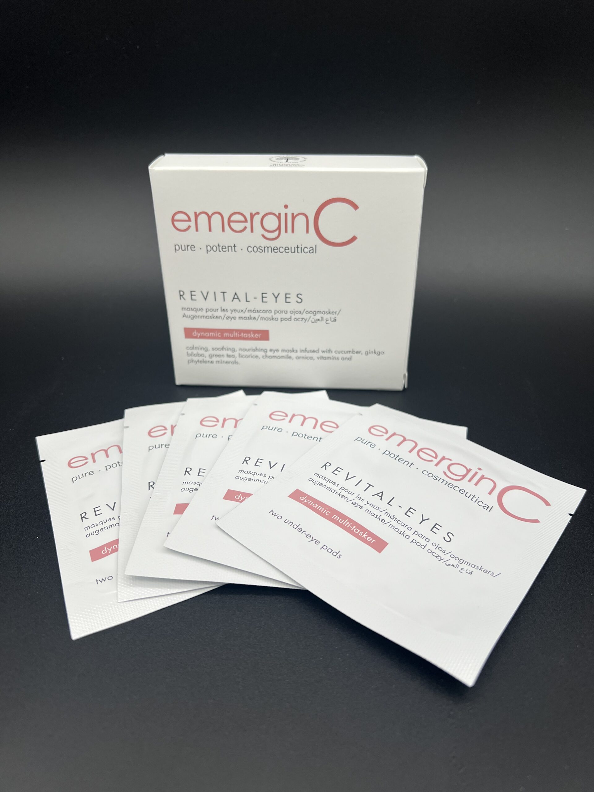 Emergen-C packets arranged in front of a product box on a dark surface.