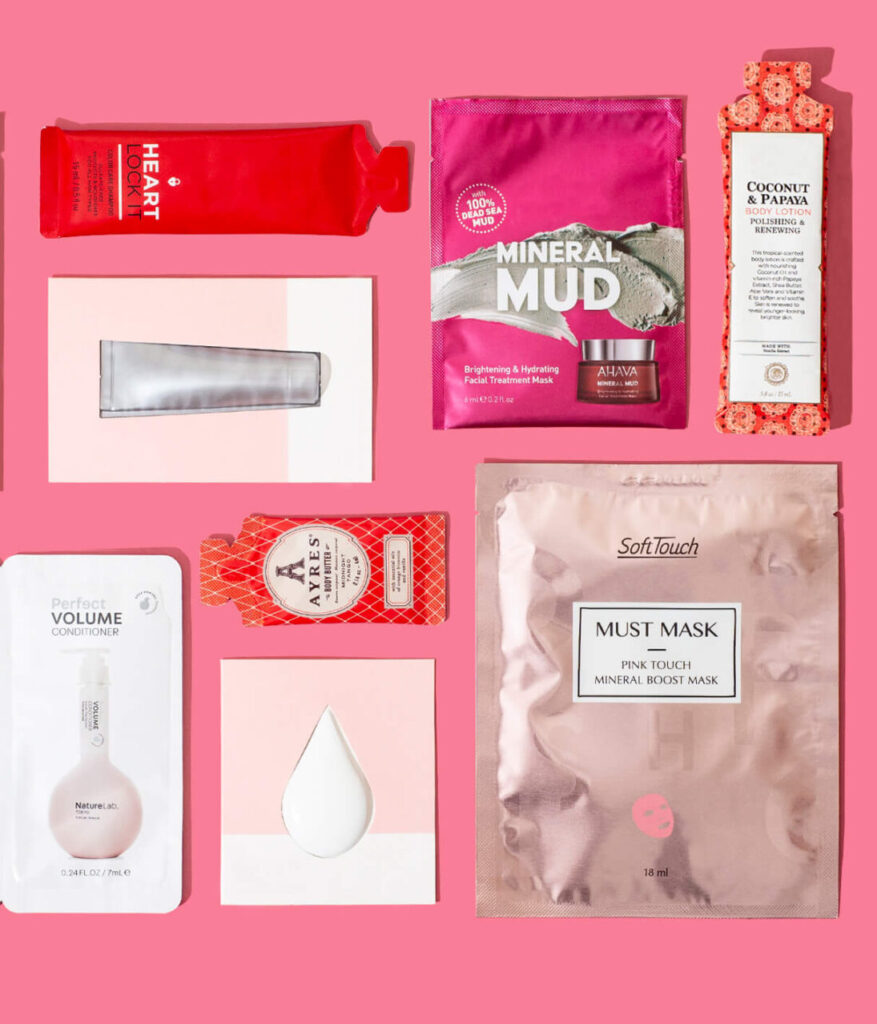 Flat lay of various skincare and beauty products arranged on a pink background.