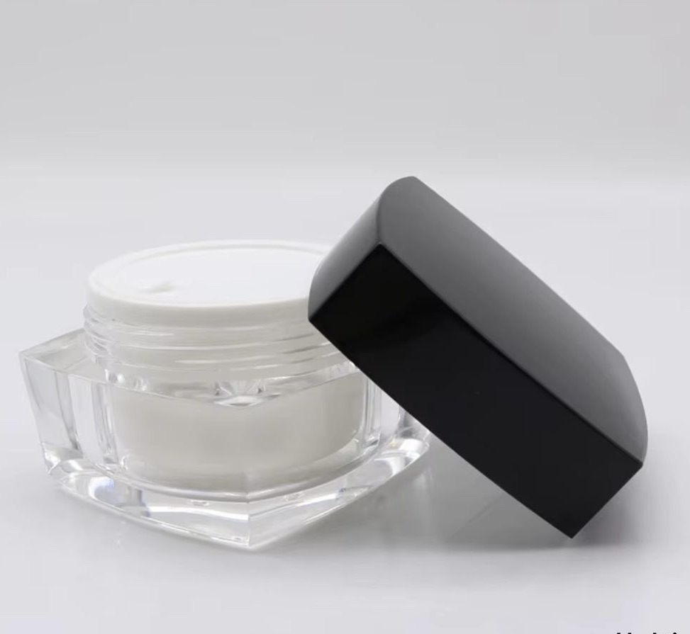 Open cream jar with black lid.