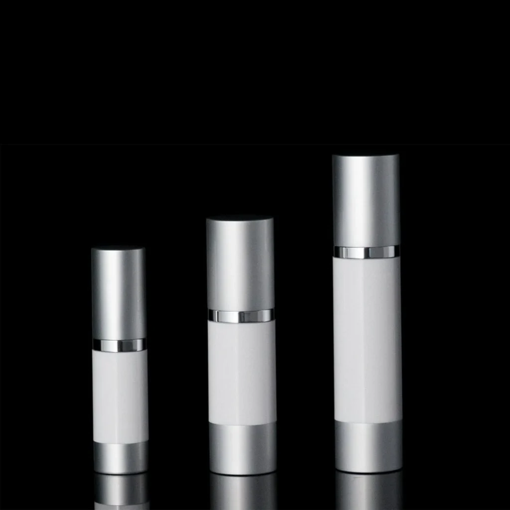 Three sleek silver and white cosmetic bottles of varying sizes against a black background.