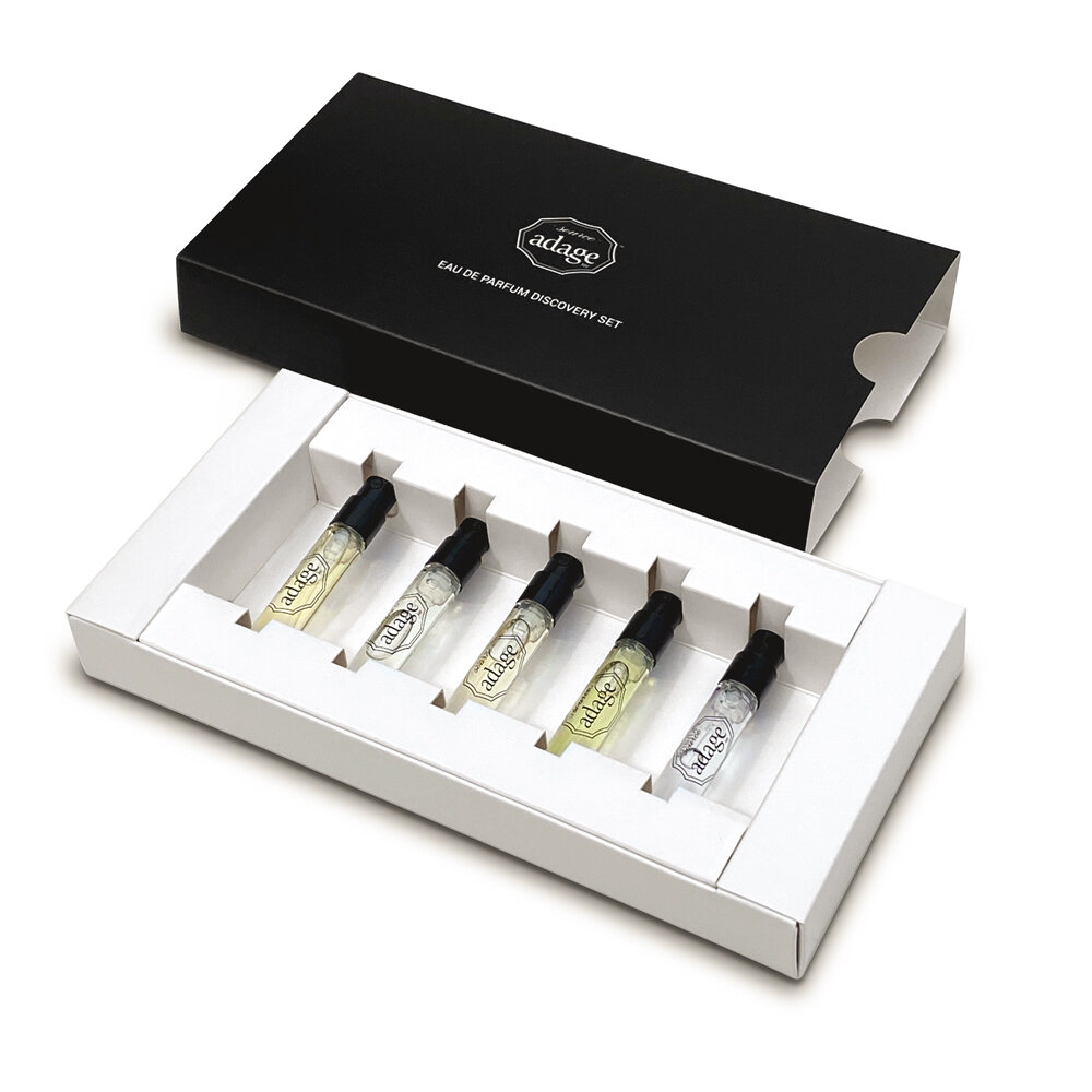 Luxury perfume sample set with six elegant glass vials in a black and white box.